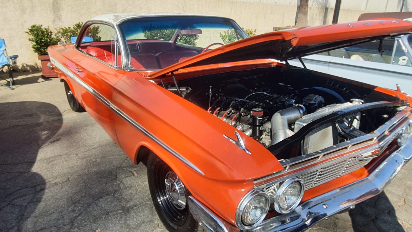 Pomarańczowy Chevrolet Impala 1961 z nowoczesnym silnikiem