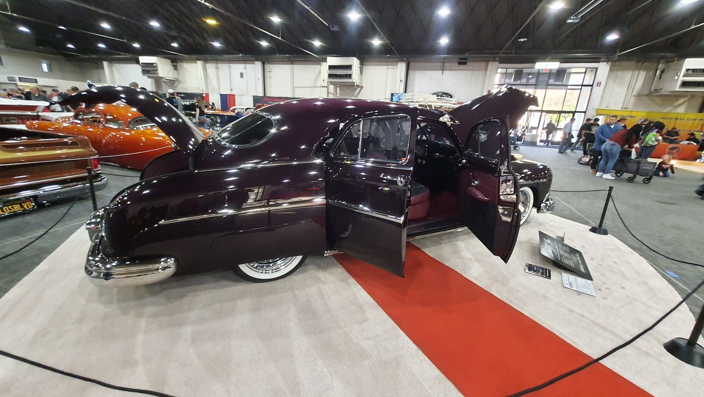Ciemnośliwkowy kustom z lat 40. z otwartymi drzwiami i maską