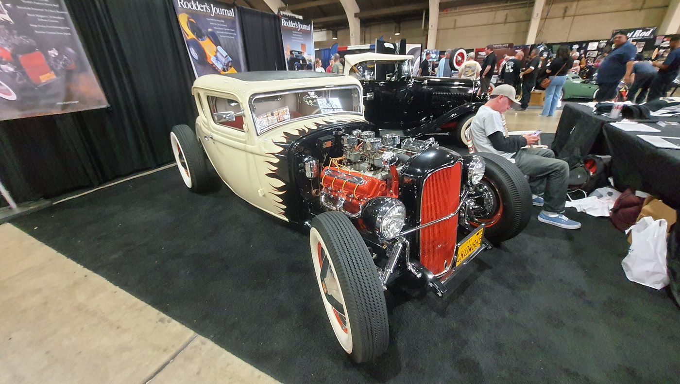 Biały Ford Model A coupe z czerwonymi felgami na stoisku Rodder's Journal